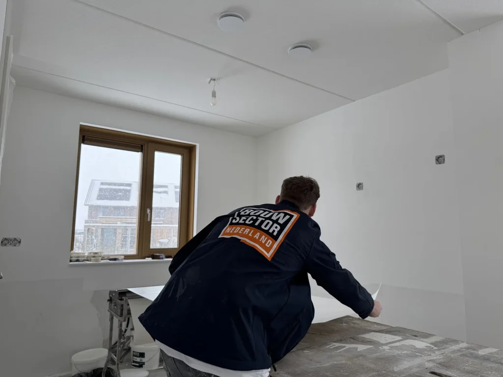 Behanger van Bouwsector Nederland pakt een baan vlies van de plaktafel in een nieuwbouwwoning
